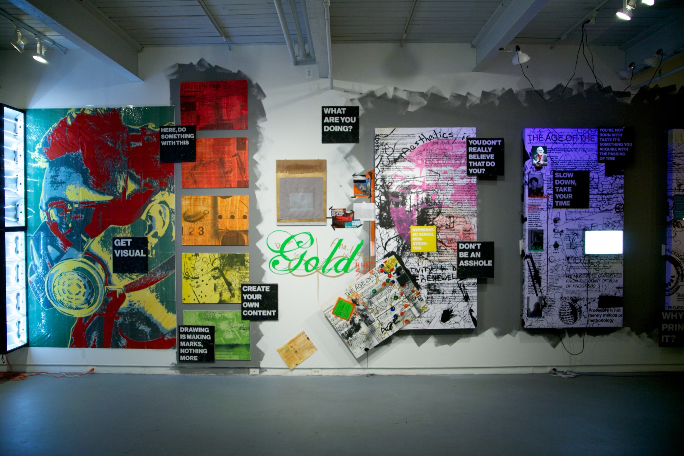 Wide finished installation view with illuminated panels, layered paintings, direct-address text, cables, and collage spanning the gallery wall.