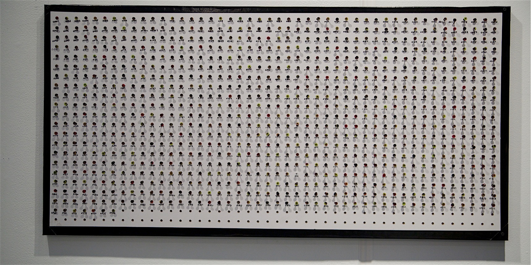 Hundreds of colored fasteners are arranged in a rectangular grid, each marked with a handwritten number.